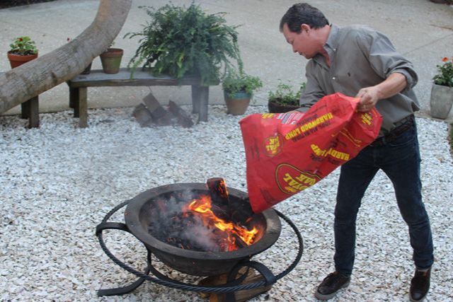 adding charcoal to wood fire for cooking