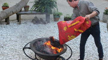 adding charcoal to wood fire for cooking